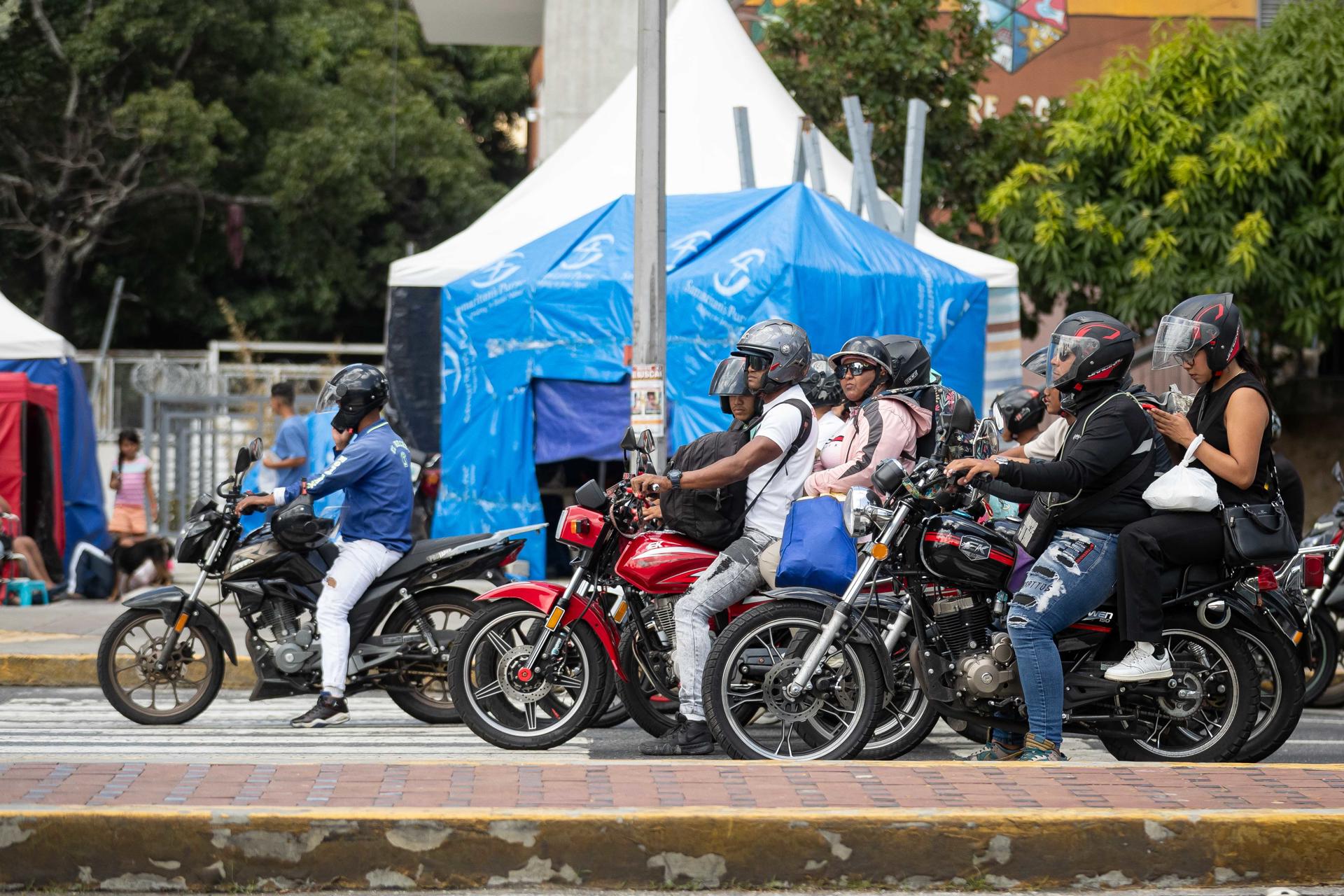 Personas transitan en moto este viernes, en Caracas (Venezuela). EFE/ Ronald Peña R