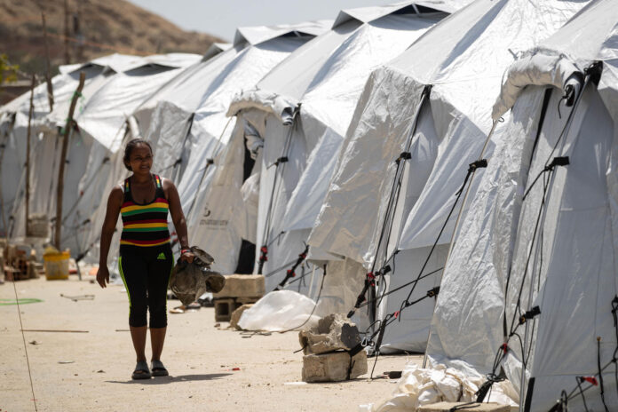 Una mujer fue captada este 24 de julio al caminar al lado de un conjunto de carpas en un albergue transitorio para personas afectadas por los terremotos de hace un mes en Venezuela, en Catia La Mar (La Guaira, Venezuela). EFE/Ronald Peña
