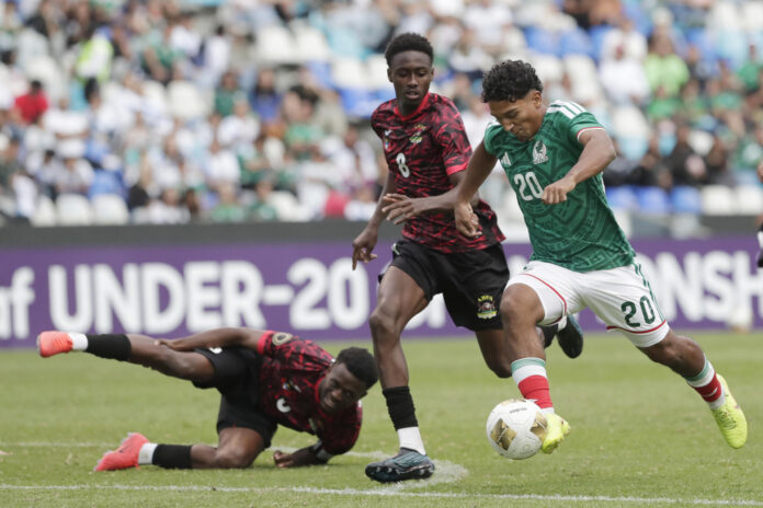 El mexicano Diego Ramírez (d) supera al defensor de Antigua y Barbuda Obediah Browne (c) durante el partido del torneo clasificatorio para los Juegos Olímpicos de Los Ángeles 2028 jugado este viernes en el estadio Cuauhtémoc de Puebla. EFE/ Hilda Ríos
