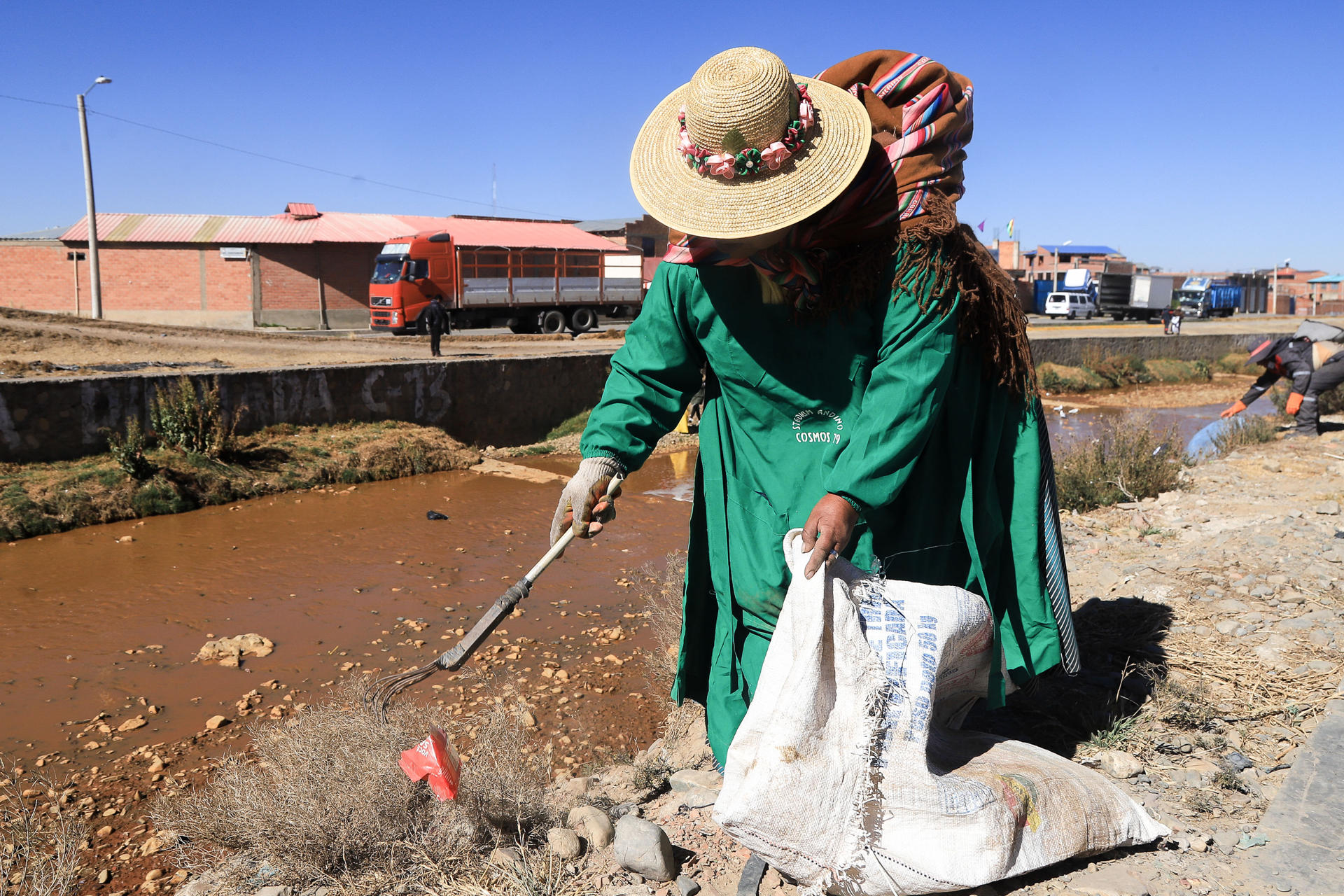 Una mujer aimara participa en una jornada de limpieza del río Seke, contaminado por basura y otros desechos que desembocan en el lago Titicaca, este sábado en El Alto (Bolivia). EFE/ Gabriel Márquez