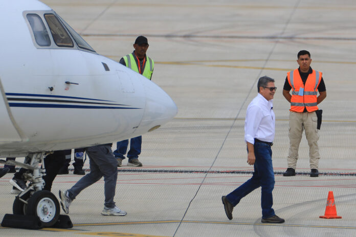 El expresidente hondureño Juan Orlando Hernández (c) (2014-2022) caminando este domingo, a su llegada al Aeropuerto Internacional de Palmerola en Comayagua (Honduras). EFE/ Gustavo Amador
