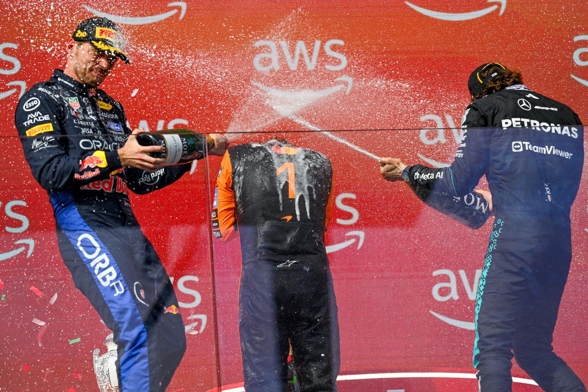 Mogyorod (Hungría), 26/07/2026.- El inglés Lando Norris (McLaren, centro), último campeón del mundo, que repitió su victoria del año pasado al ganar este domingo el Gran Premio de Hungría, el undécimo del Mundial de Fórmula Uno, es regado con champán, en el podio, por el neerlandés Max Verstappen (Red Bull, i.), que fue segundo; y el italiano Andrea Kimi Antonelli (Mercedes. d.), el líder del certamen, que acabó tercero. EFE/EPA/Zsolt Czegledi