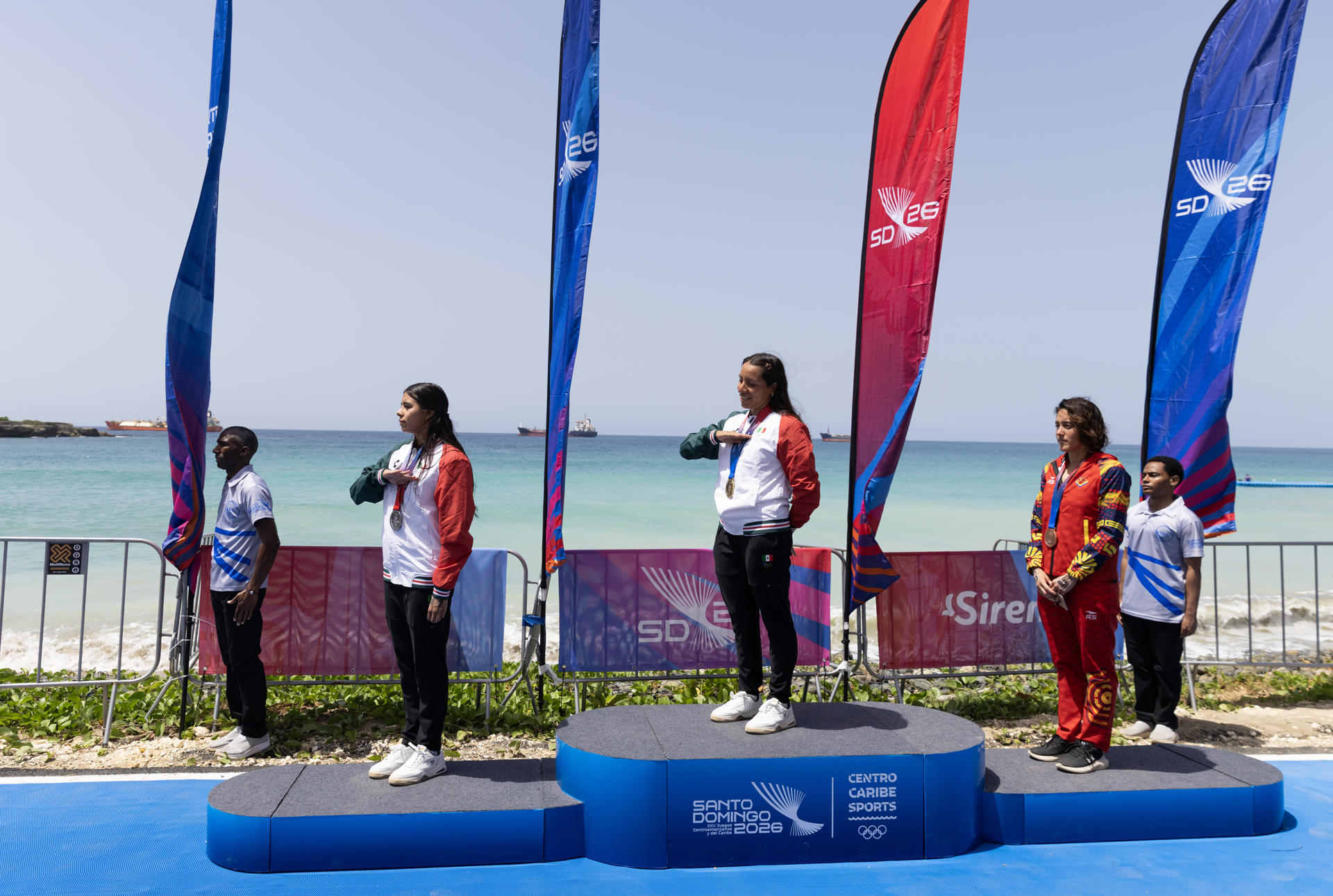 Dalia Moreno (c), de México, medalla de oro; Yuritzi Salgado (i) de México, plata; y Paola Pérez, de Venezuela, bronce, posan en el podio este domingo al finalizar la competencia de 3K de Natación en Aguas Abiertas de los XXV Juegos Centroamericanos y del Caribe Santo Domingo 2026. EFE/ Orlando Barría
