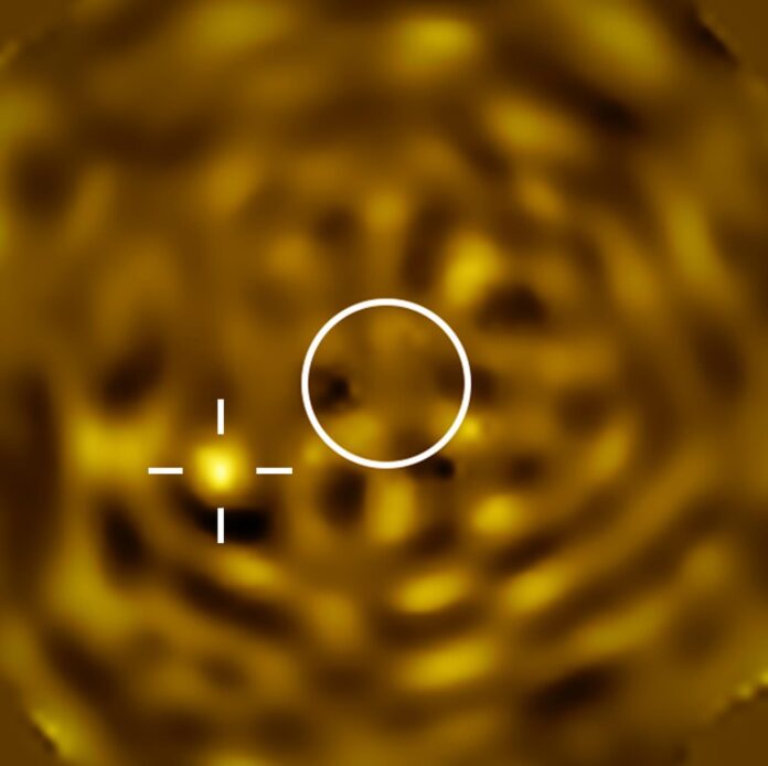 Esta instantánea, tomada con el VLT (Very Large Telescope) del ESO, muestra la imagen más nítida hasta la fecha de lo que probablemente es Betelgeuse B, una estrella orbitando Betelgeuse. El círculo indica el tamaño de Betelgeuse, que ha sido eliminada. La fuente brillante a la izquierda, marcada con un punto de mira, es consistente con la posible Betelgeuse B. Fotografía facilitada por ESO/M. Montargès et al.
